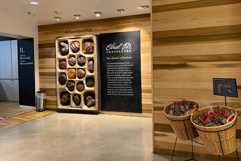 A giant box of chocolates against a multi-colored wood wall at Ethel M.