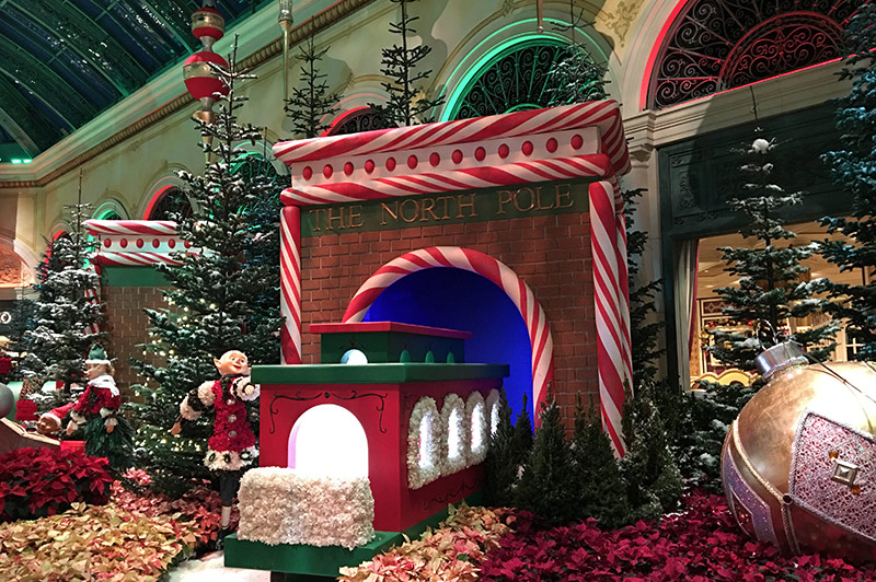 Christmas scene with train coming through tunnel, elves and leaves bright orange and red in color