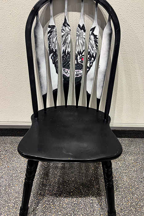 a black chair painted with a creepy monsterous face creating a cage-like effect