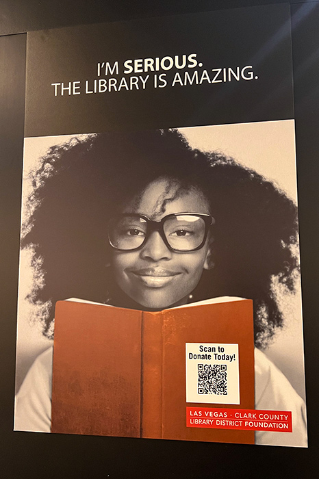 poster of a young black girl with glasses holding a book, the caption on the poster is "I'm serious. The library is amazing."