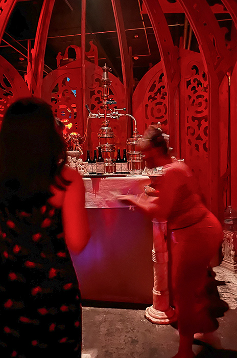 a woman blurs as she serves rum tastings from the altar of the chapel room of Lost Spirits distillery