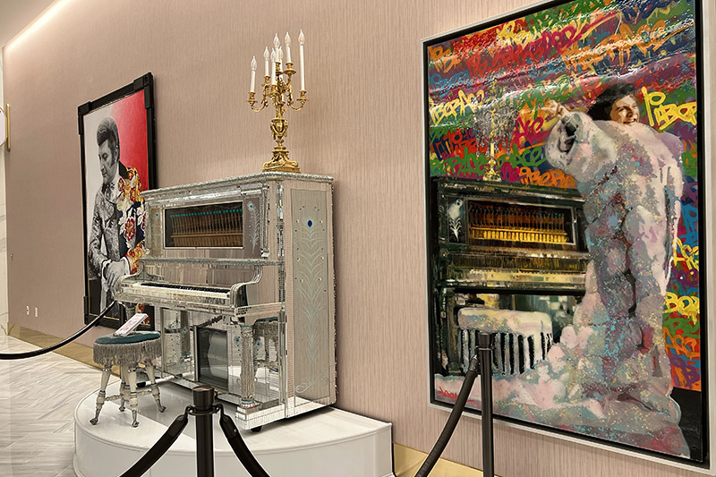 a display with two paintings of Liberace and Liberace's piano near Conrad lobby at Resorts World Las Vegas