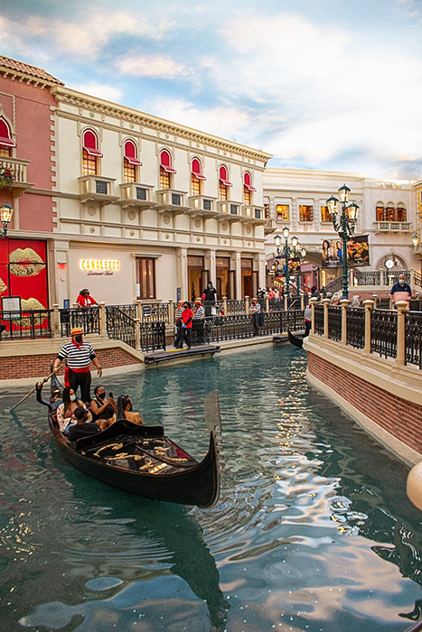 A gondola moves through a canal in front of shops in the Venetian resort